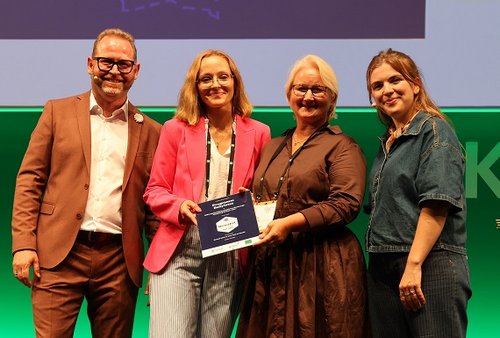 Bild der Verleihung, Jana Jürges und Nicole Hellwig halten die Urkunde in die Kamera
